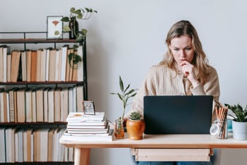 Woman writing meeting cancelation email on laptop